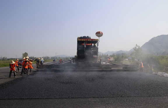 2019年8月，宜春經(jīng)開(kāi)區(qū)S311路面攤鋪現(xiàn)場(chǎng)，工友們輔助路面兩側(cè)的分料、補(bǔ)窩等作業(yè)